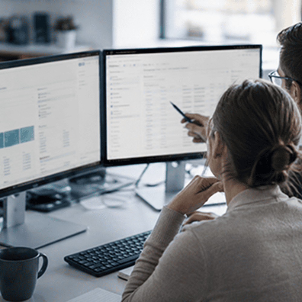 Zwei Mitarbeitende arbeiten mit Microsoft Dynamics 365 Business Central und einem Dokumentenmanagementsystem an einer integrierten Lösung.
